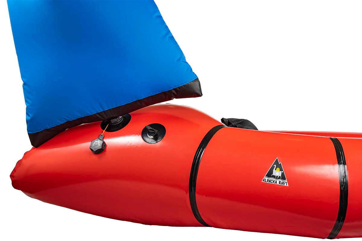 Close-up of a red inflatable packraft with blue fabric, featuring valves and a logo.