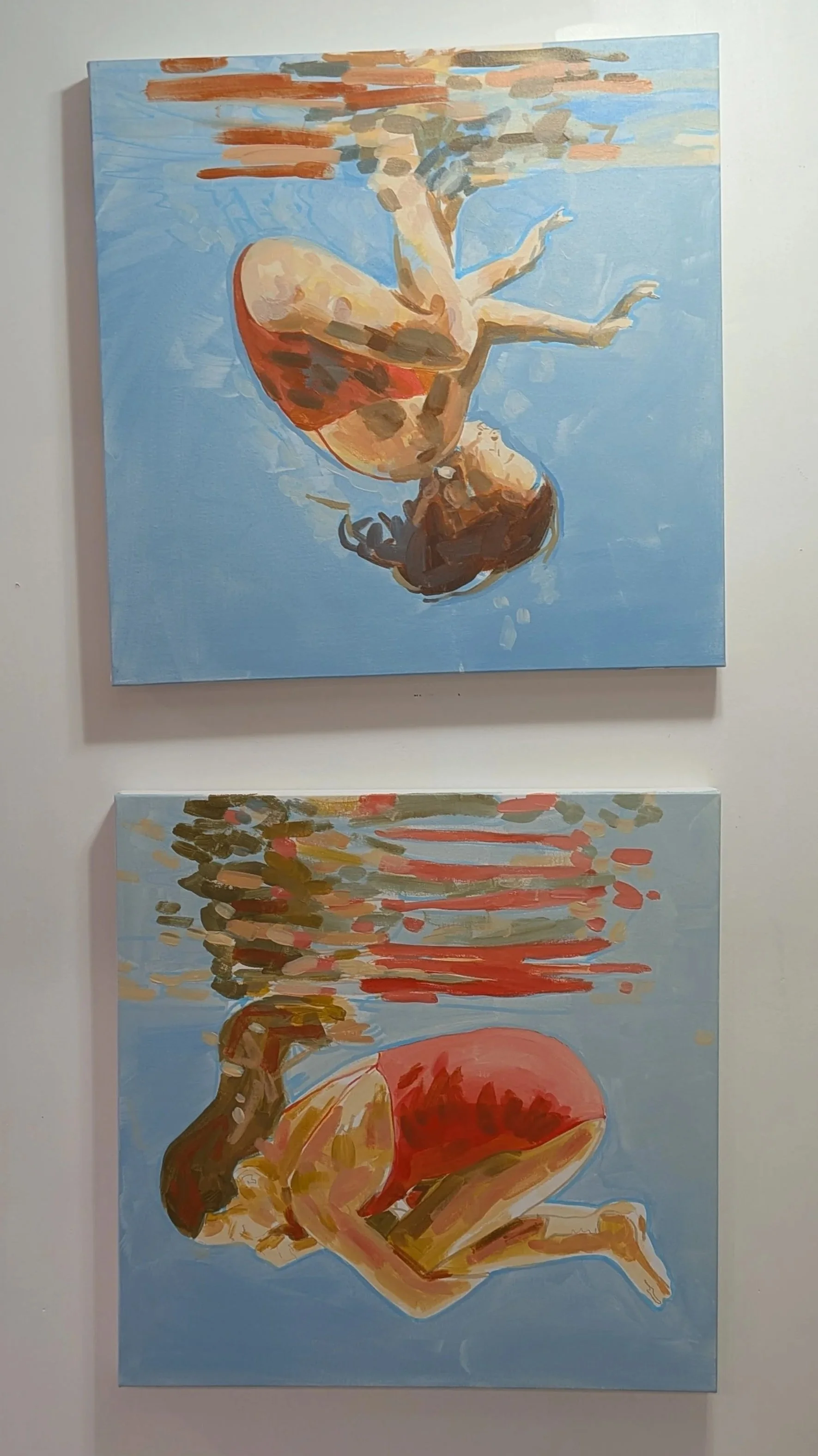 Two swimmer paintings by Vanessa Corrigall with red bathing suits and water reflections