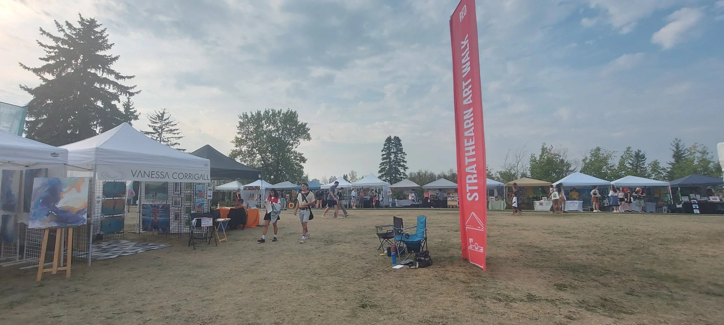 Strathearn Art Walk in Edmonton with Vanessa Corrigall art booth in the Red Zone, outdoor tents, visitors walking, and festival atmosphere in the river valley