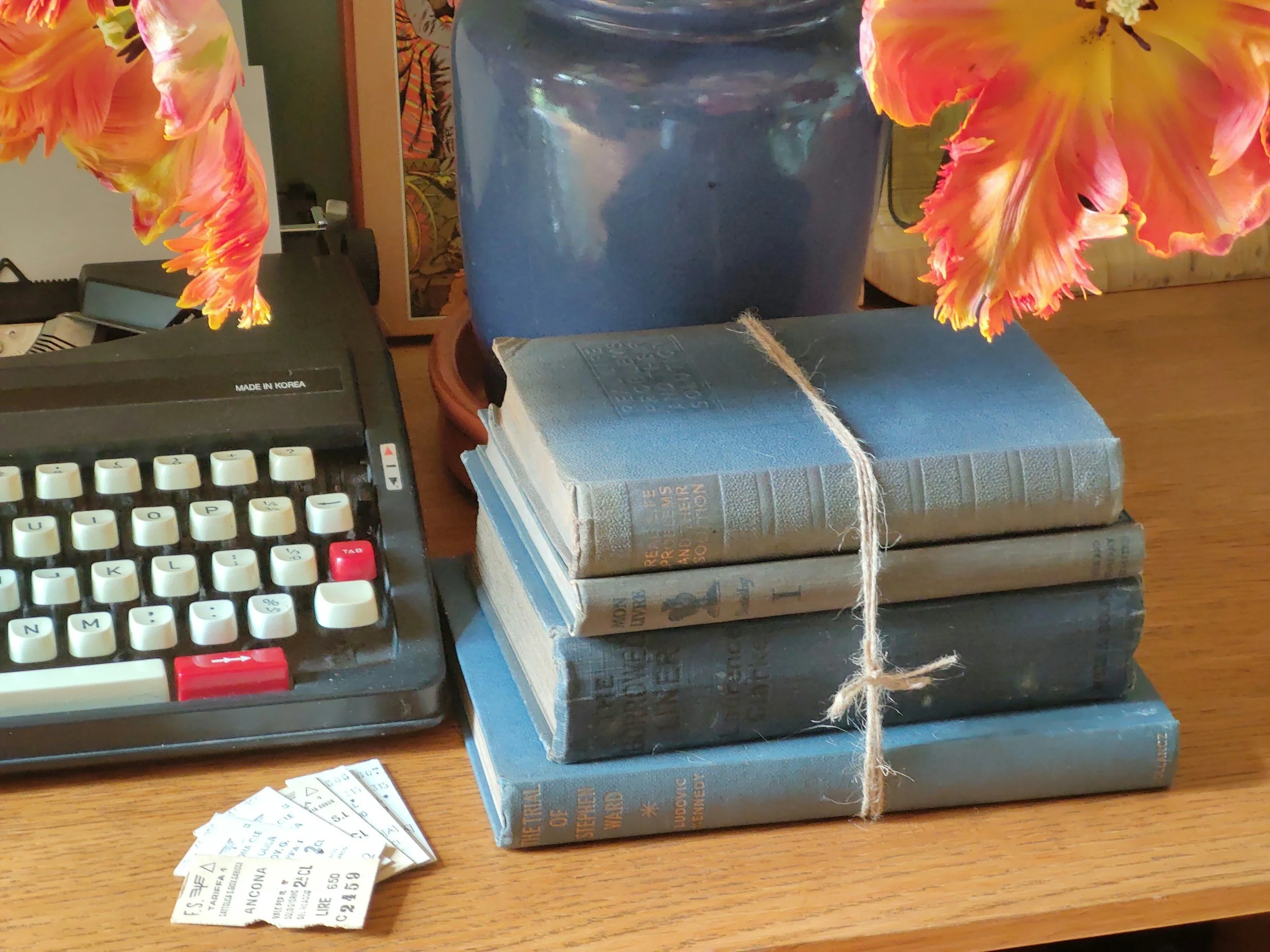 Stack of books with typewriter and flower in vase