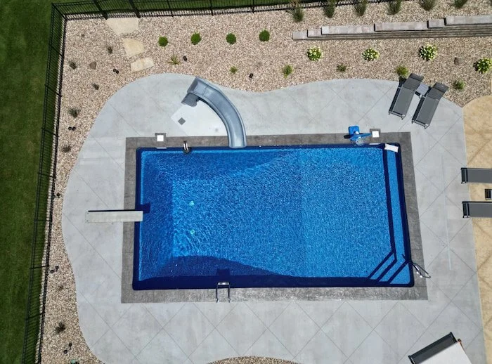Vinyl liner pool installation showing 18x40 Diver pool with a GLI Cayman Mystic Light Blue liner, granite left turn Typhoon slide, deck jets, step and bench combo, and 8-foot deep end.
