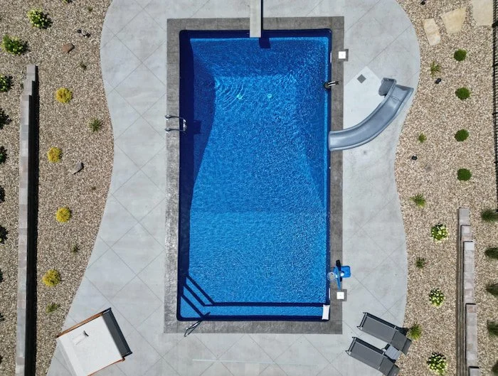 Complete backyard retreat featuring 18x40 vinyl liner swimming pool with vibrant blue GLI Cayman finish, professional-grade 8-foot deep end for diving, decorative deck jets, multi-level seating areas, and professionally landscaped surroundings with n