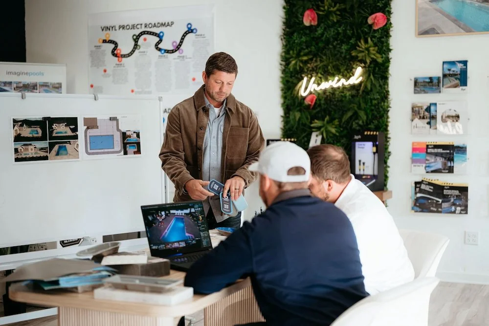 A Kansas City pool contractor reviewing vinyl liner pool designs and material samples with a client in a modern showroom.