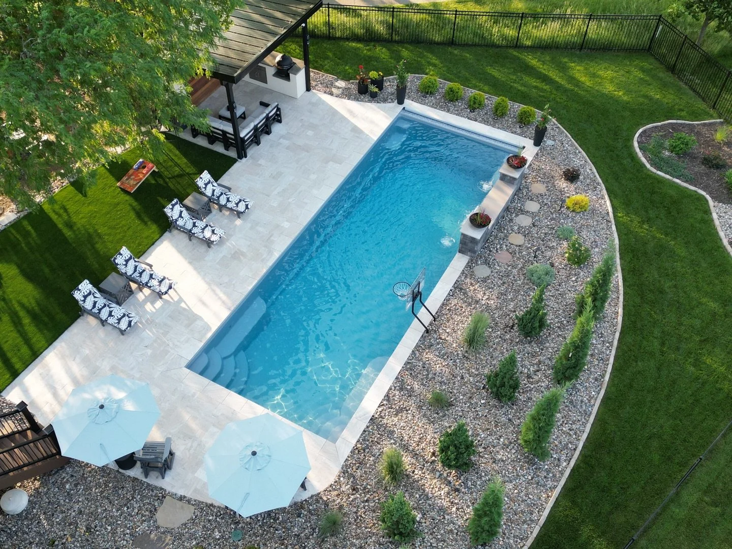 A Thursday Goliath fiberglass pool is the centerpiece of this backyard, framed by travertine pavers, a custom outdoor kitchen, and integrated water features. Designed for everyday use, entertaining, and long-term livability.

This is an elevated back