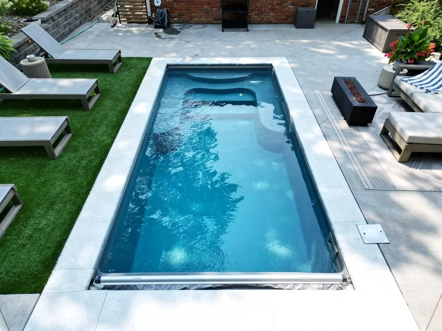 A Thursday Sea Turtle fiberglass pool in the Diamond color anchors this backyard, creating that bright, clean blue water that immediately draws you in. Ice marble pavers frame the pool and patio, keeping the space light, cool underfoot, and refined, 