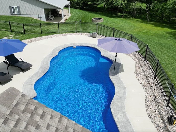 Close aerial view of the Thursday Pools Sun Day freeform fiberglass pool showcasing the 16-inch decorative coping band, sun deck bubblers, and deep Maya blue color, built by Tiger Pool and Patio in Kansas City.