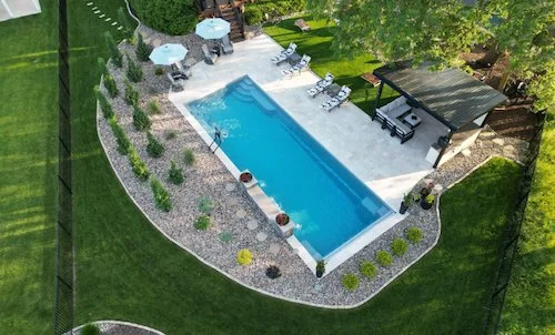 Tiger Pool and Patio fiberglass inground pool installation in Kansas City—Thursday Pools Goliath 16x41 in Diamond with travertine paver patio, pergola, and lush backyard landscaping.