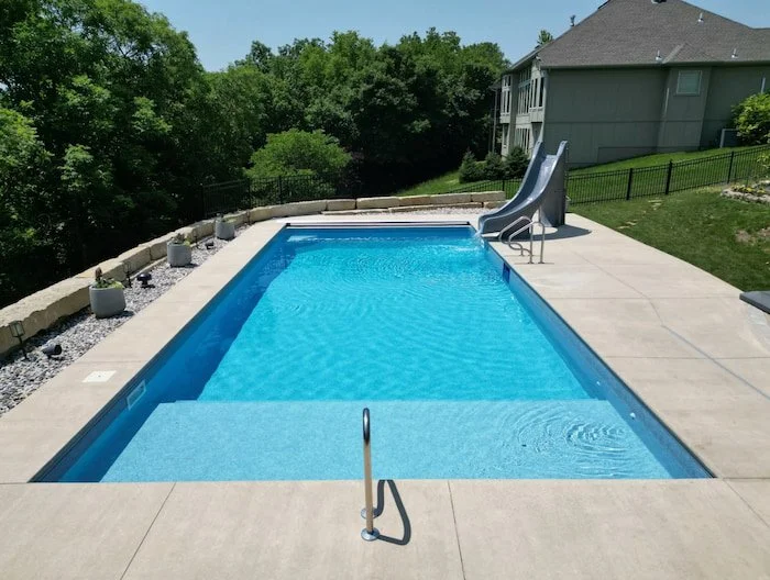 Kansas City vinyl liner pool company Tiger Pool and Patio delivers a premium 18x40 inground swimming pool installation with a stunning GLI Cayman Mystic Light Blue liner, full-length integrated sun deck, corner bench for relaxation, automatic safety 