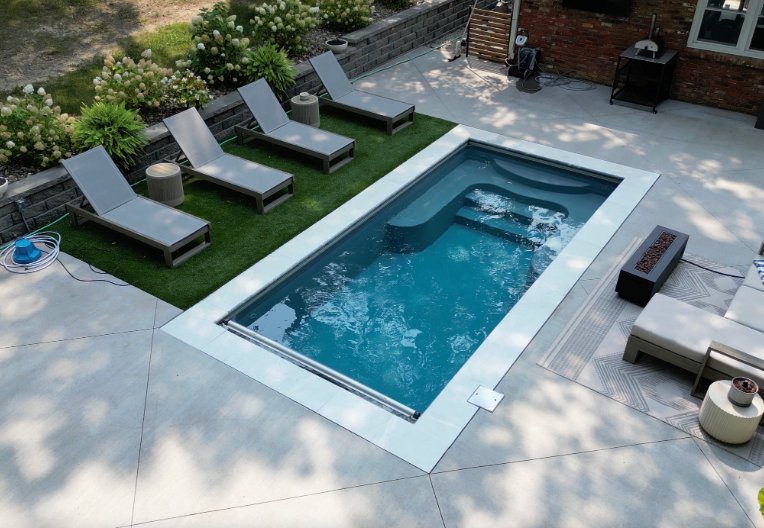 Fiberglass inground pool installed by Tiger Pool and Patio in Kansas City, featuring the Thursday Pools Sea Turtle model in Diamond with an automatic safety cover and artificial turf patio.