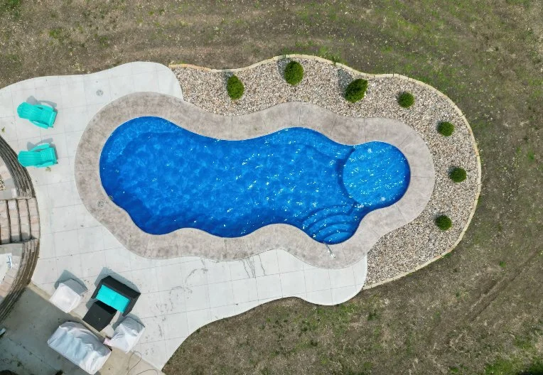 Aerial view of a freeform fiberglass inground pool installed by Tiger Pool and Patio in Kansas City—Thursday Pools Wellspring 16x40 in Maya Blue with coping band and bubblers.