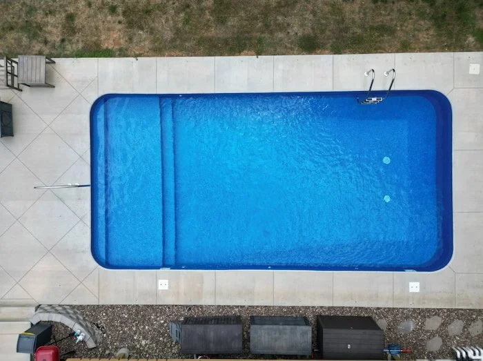 Kansas City vinyl liner pool builder Tiger Pool and Patio showcases craftsmanship with a 16x32 pool featuring a stunning Jamaica floor pattern without a border, a continuous full-length sun deck creating a generous shallow lounge area, a stylish arti