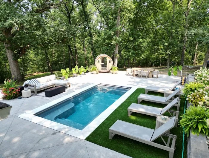 A Thursday Pools Sea Turtle fiberglass inground pool in Diamond with turf lounge area, ice coping stones, and a cedar barrel sauna—a complete backyard wellness retreat installed by Tiger Pool and Patio.
