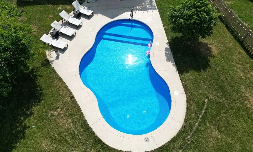 A 20x30 freeform vinyl liner inground pool with full-length sun deck and Blue Quartz liner, built by Tiger Pool and Patio.