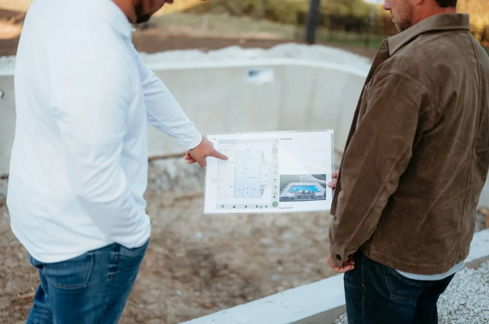 A Kansas City pool contractor reviewing inground pool designs with a homeowner on-site during pool installation.