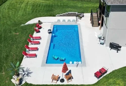 Kansas City backyard pool and patio by Tiger Pool and Patio featuring a Thursday Pools Aspen 16x35 in California Blue, complete with a sunken outdoor kitchen and stainless steel waterfall.