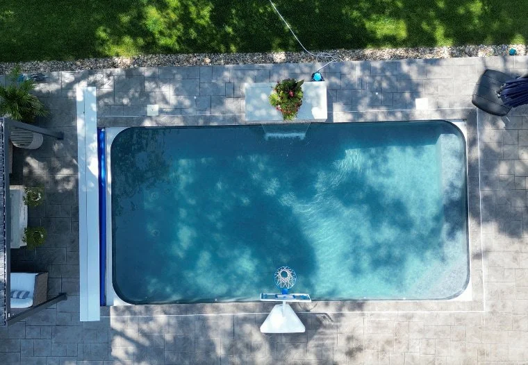 An 18x36 vinyl liner pool remodel by Tiger Pool and Patio in Kansas City featuring Shelter Cove liner, full-width bench, corner steps, water feature wall, and automatic safety cover.