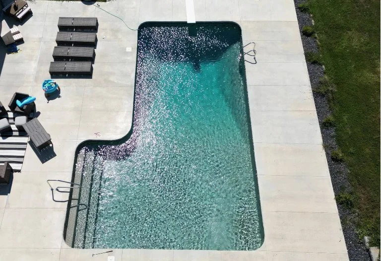 An L-shaped vinyl liner inground pool with diving board and full-length steps installed by Tiger Pool and Patio.