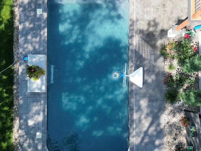 Aerial view of Kansas City inground pool service showing a 18x36 pool remodel with Merlin Shelter Cove liner, automatic safety cover, full-width bench with corner steps, and diving board installation.