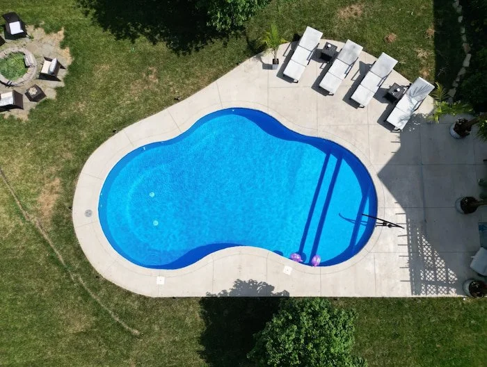 Kansas City inground pool installation featuring 20x30 Mountain Lake fiberglass pool with a custom Merlin Blue Quartz vinyl liner and a full-length sun deck with a black artisan handrail.