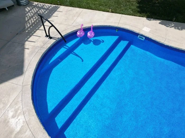 Close-up of a fiberglass inground pool sun deck and steps with a Merlin Blue Quartz vinyl liner installed by Tiger Pool and Patio in Kansas City.