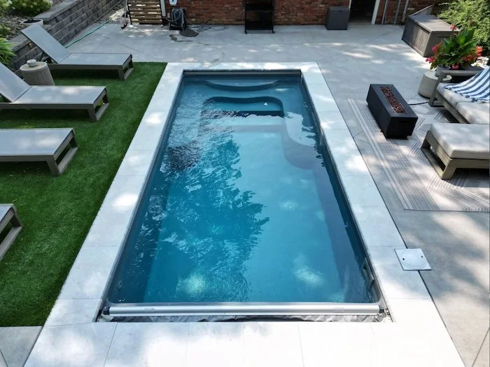 Ground-level view of a Thursday Pools Sea Turtle fiberglass pool in Diamond with automatic safety cover, ice coping, and artificial turf—a modern small inground pool design by Tiger Pool and Patio in Kansas City.