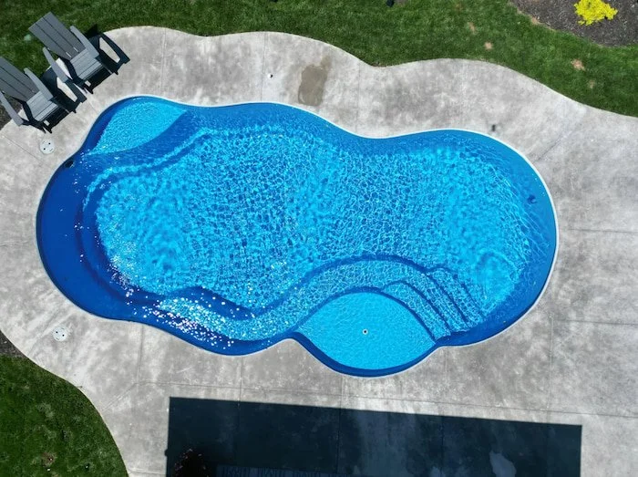 Direct overhead view of a Thursday Pools Sun Day 15x30 freeform fiberglass inground pool in California Blue showing the sun deck and entry steps.