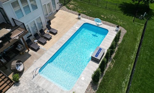 Tiger Pool and Patio vinyl liner pool installation—14x30 rectangular inground pool with full-length sun deck, water feature wall, and Serene Tile liner.