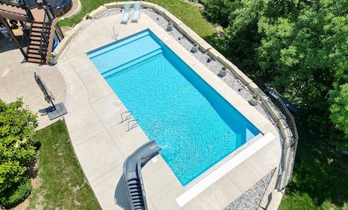 An 18x40 vinyl liner inground pool with tidal wave slide, full-length sun deck, and automatic safety cover built by Tiger Pool and Patio.