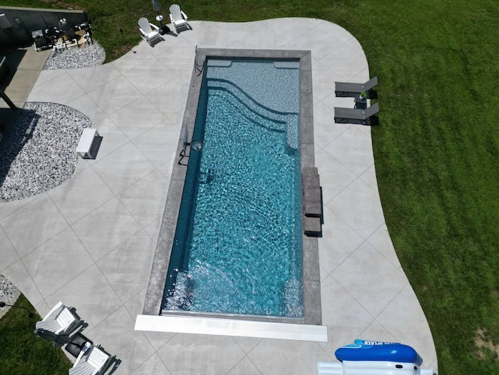 Elevated view of a Thursday Pools Aspen 16x40 fiberglass inground pool in Diamond with automatic safety cover, sheer descent waterfall, and decorative coping, installed by Tiger Pool and Patio in Kansas City.