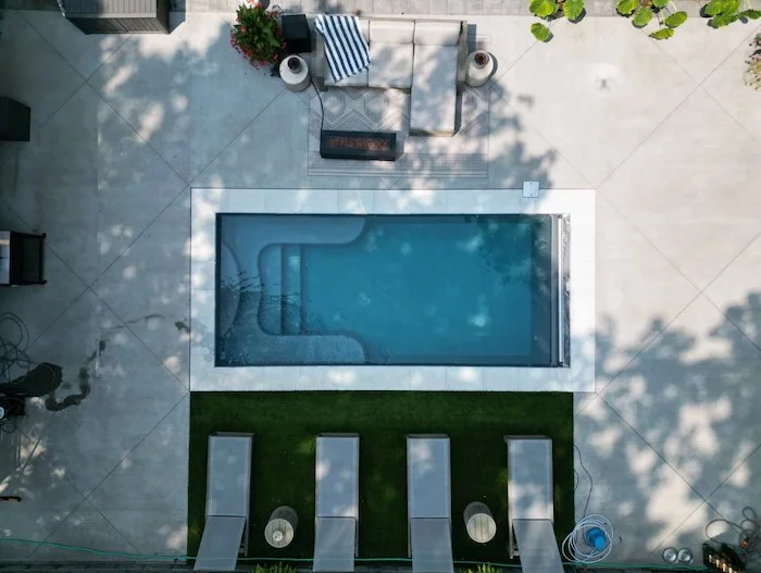 Overhead aerial view of a Thursday Pools Sea Turtle fiberglass inground pool in Diamond with ice coping stones, a turf lounge section, and a large concrete patio surround.