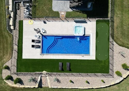Aerial view of a Tiger Pool and Patio fiberglass inground pool installation in Kansas City—Thursday Pools Aspen 16x40 in Maya Blue with spillover spa, putting green, and paver patio.