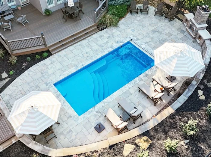 Overhead view of a Kansas City fiberglass inground pool by Tiger Pool and Patio—Thursday Pools Aspen 12x25 with automatic safety cover, silver tumbled coping, and Belgard Scandina Gray pavers.