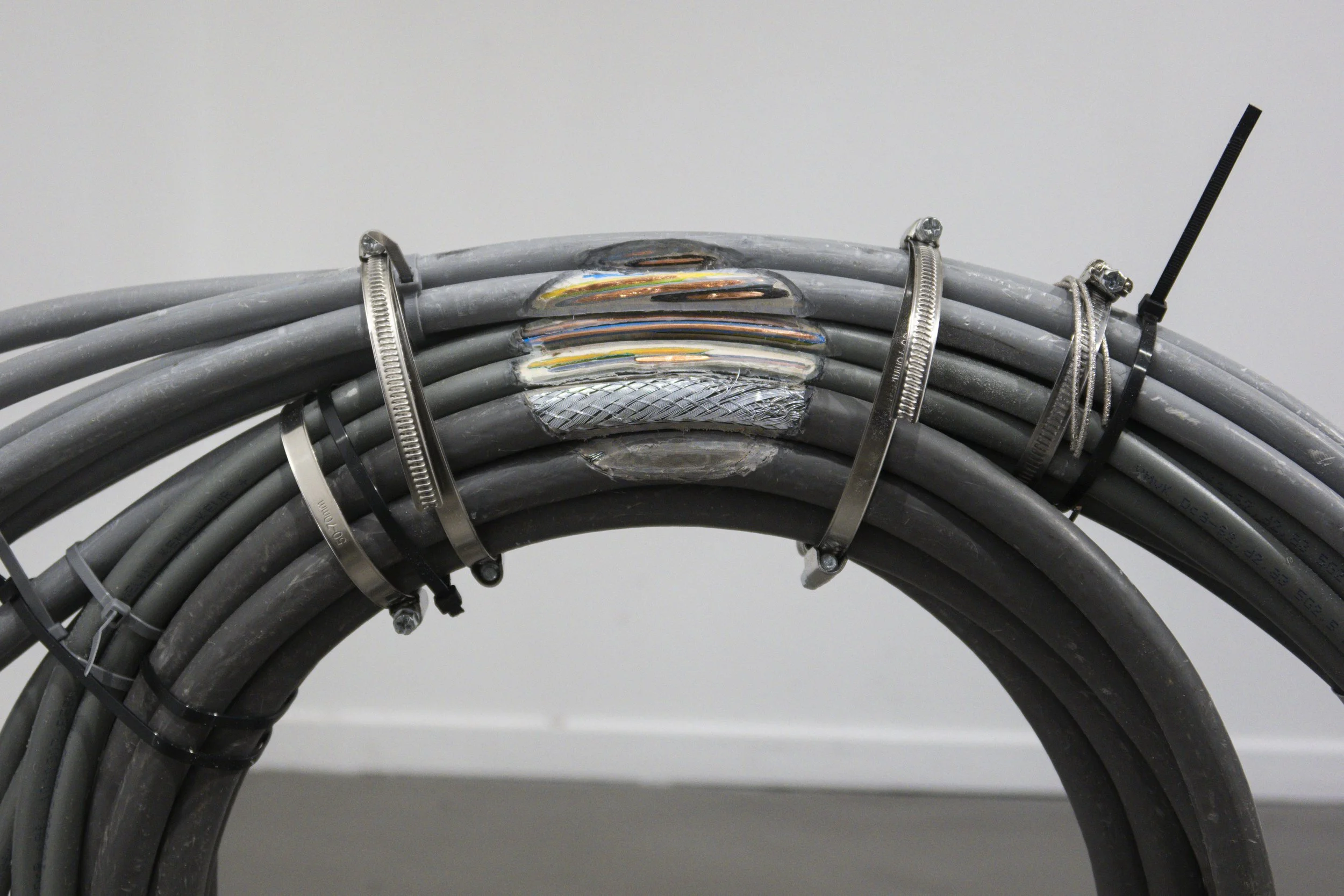 Detail of the sculpture “Sunrise,” showing cable layers held by bracelets and worm drive clamps, shown in exhibitions at Platform Stockholm and Loods 6.