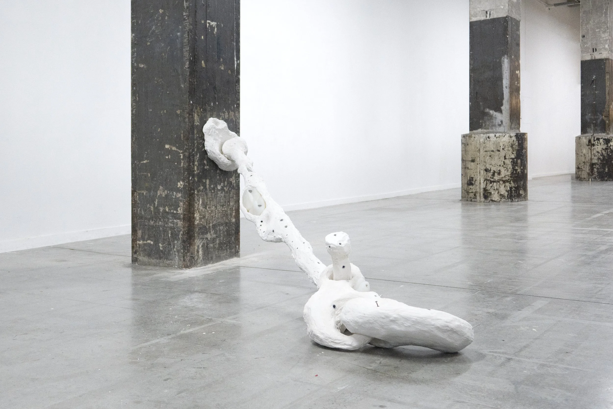 Installation view of “Wrist,” a tall plaster and silicone sculpture built from wall plugs and structural elements, exhibited at Loods 6.