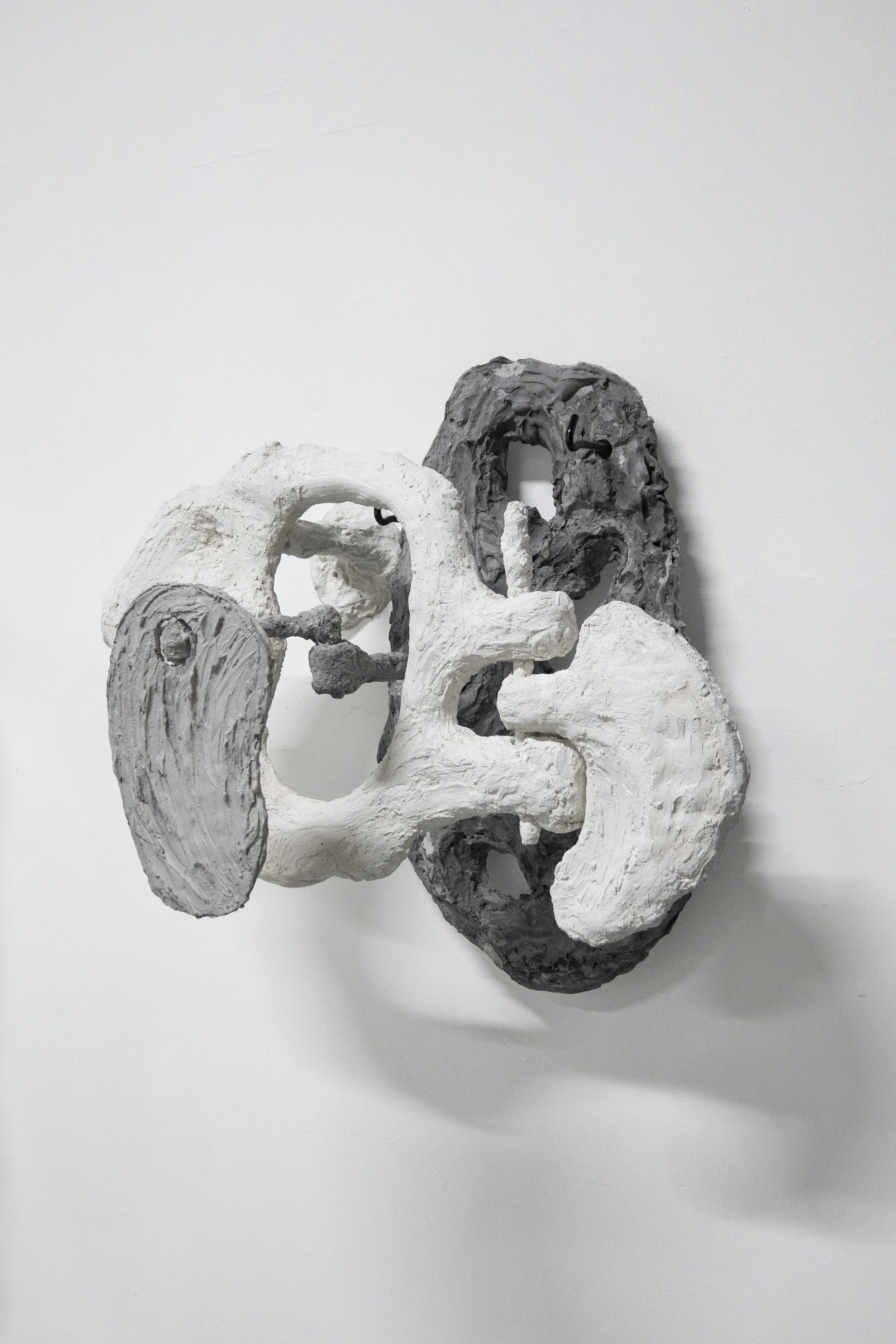 Installation view of “Bust,” a sculpture made of wall plugs, plaster and metal, combining fragmented facial geometry with industrial anchoring elements.