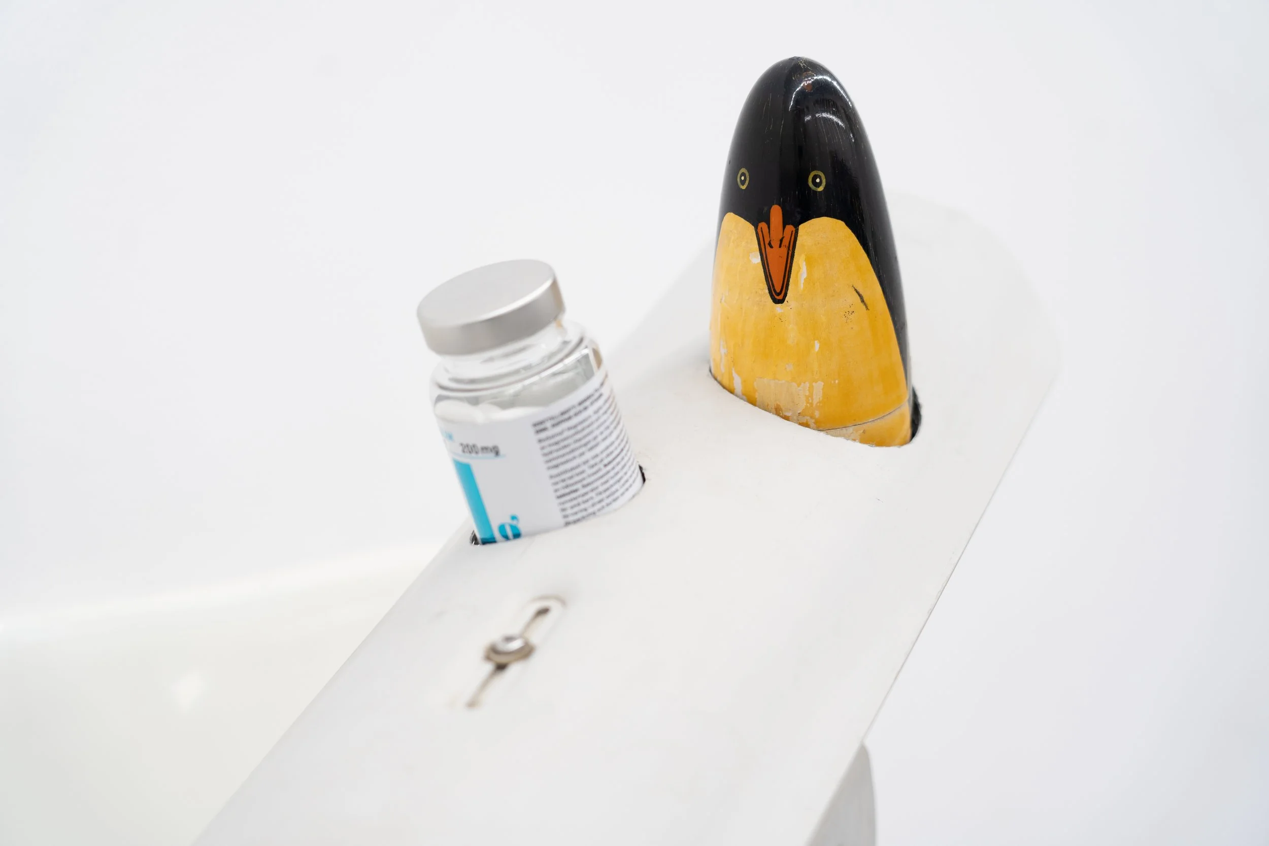 Detail of the foldable chair and wooden penguin component of the sculpture “Self-conscious.”