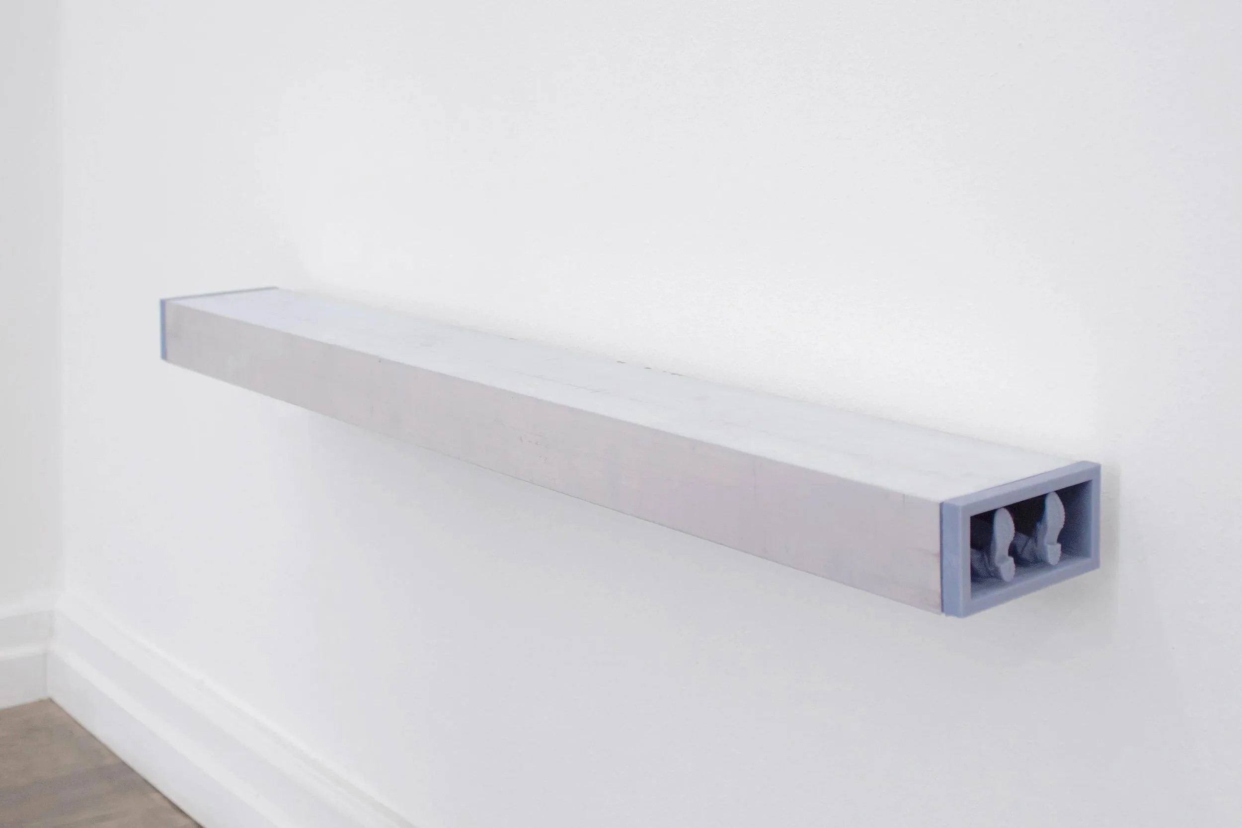 Installation view of Brink, a sculptural work featuring human-like legs with visible shoe soles emerging from an assembled structure.