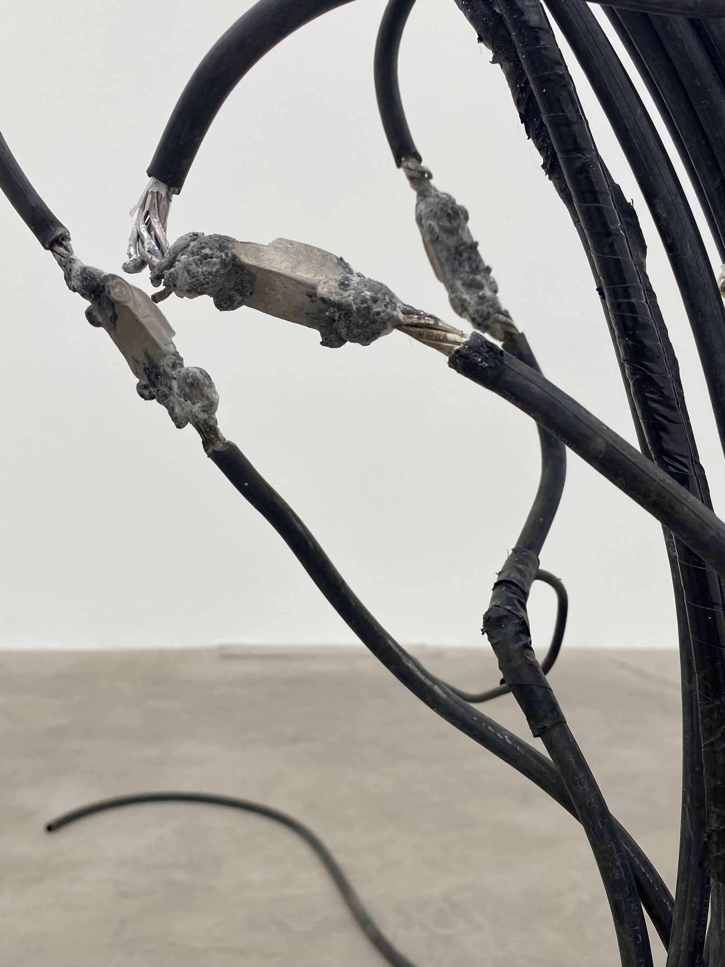 Detail of “Fossil Visions” showing carved cavities filled with small aluminium car forms embedded into a coiled electric and data cable sculpture, exhibited at guadalajara90210 under the curatorship of LAVA.