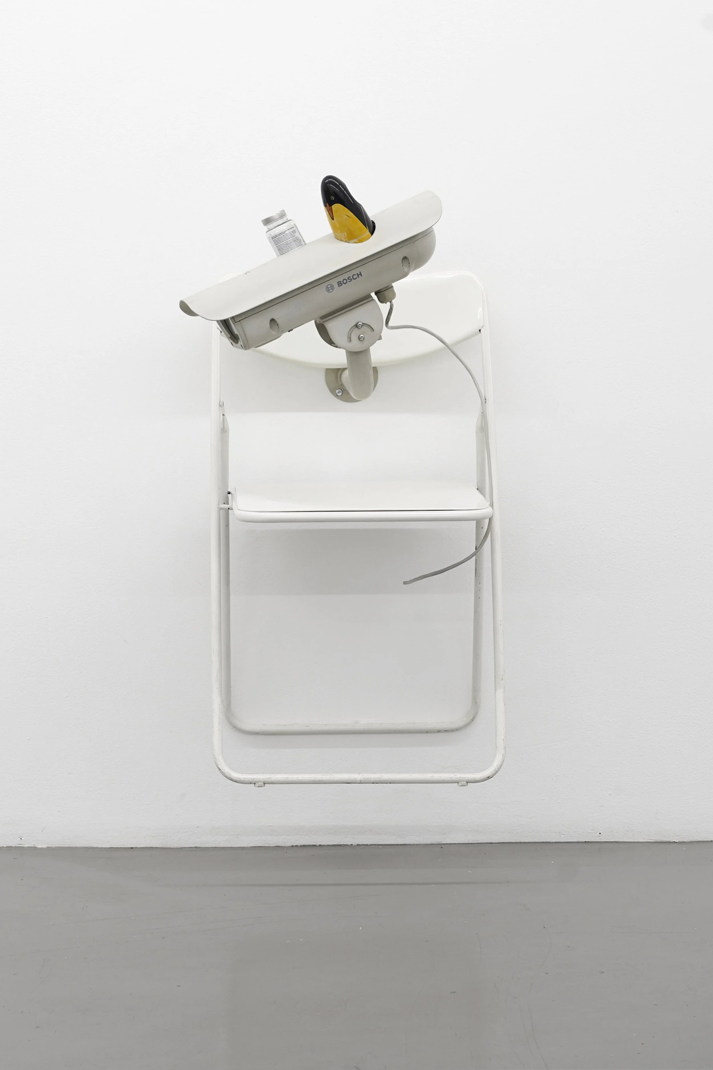 Detail of the foldable chair and wooden penguin component of the sculpture “Self-conscious.”