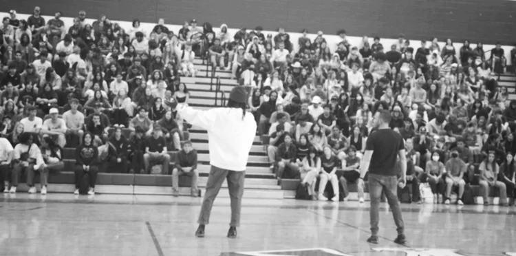 A full gym of students watching an Out of the Classroom assembly