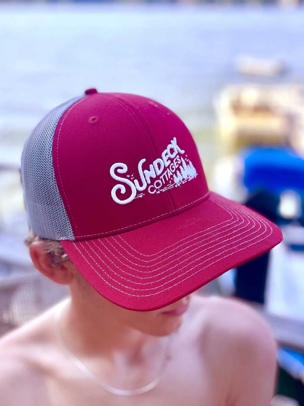 A kid wearing a Sundeck Cottages trucker hat at Lake Winnipesaukee.