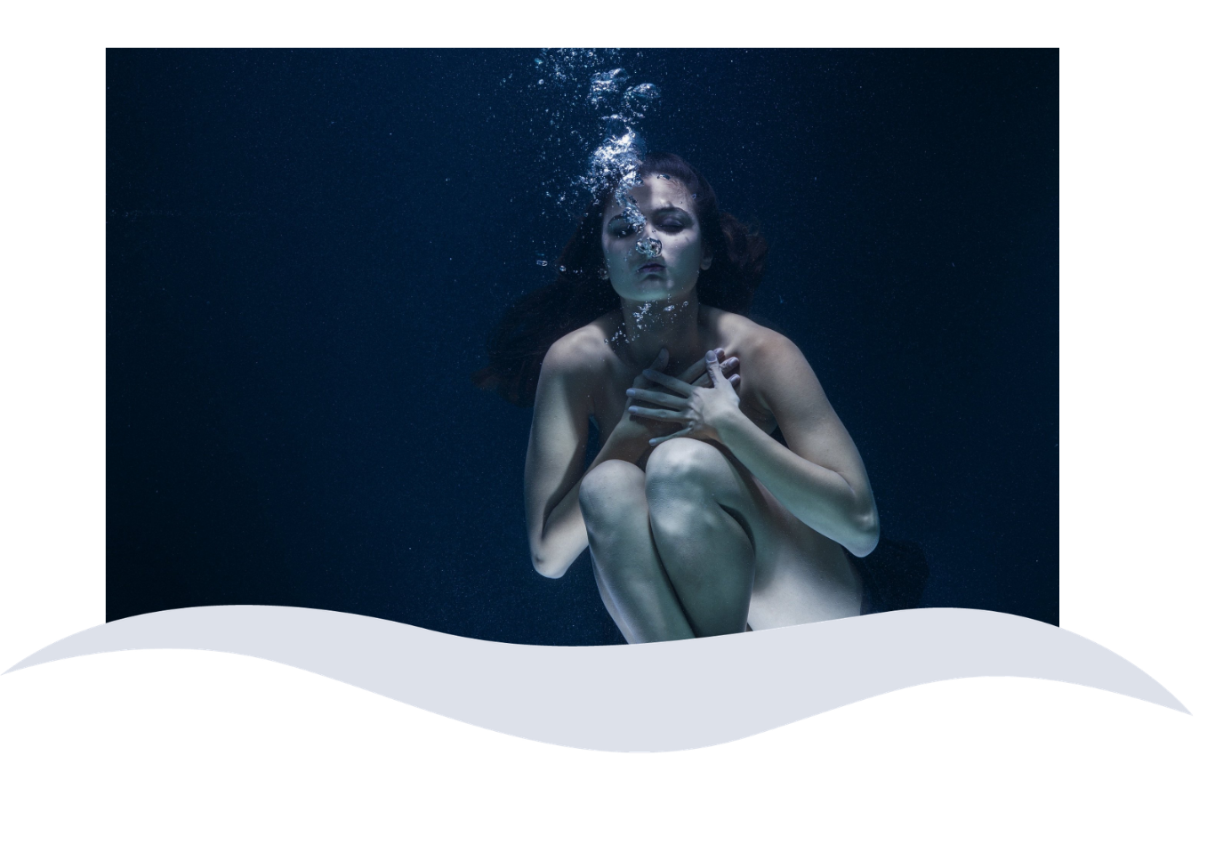 A woman underwater with dark hair, clutching her chest, eyes closed, in a dark blue environment with bubbles around her.
