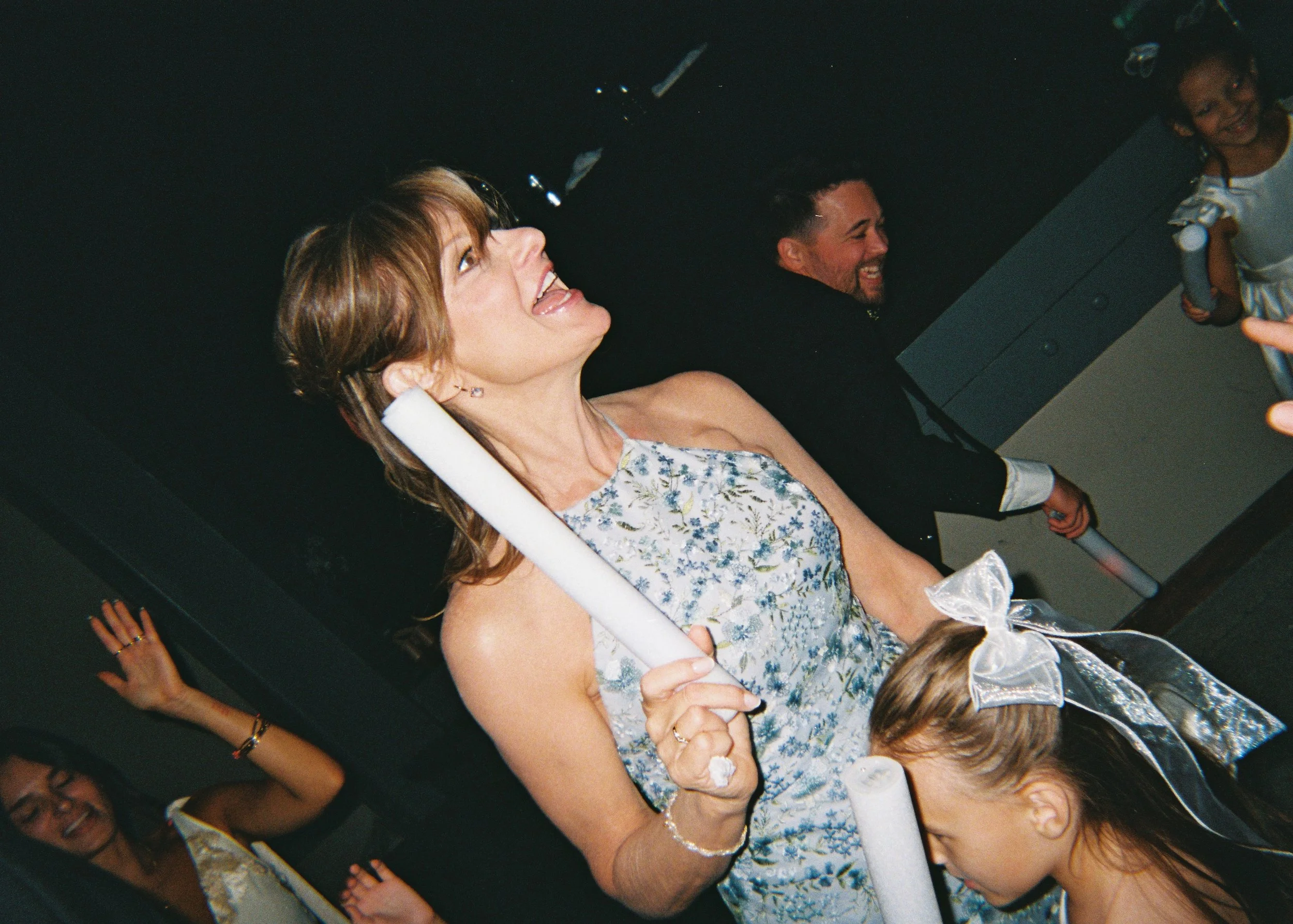 Woman with short hair smiling and celebrating with children and a man in a dark room.