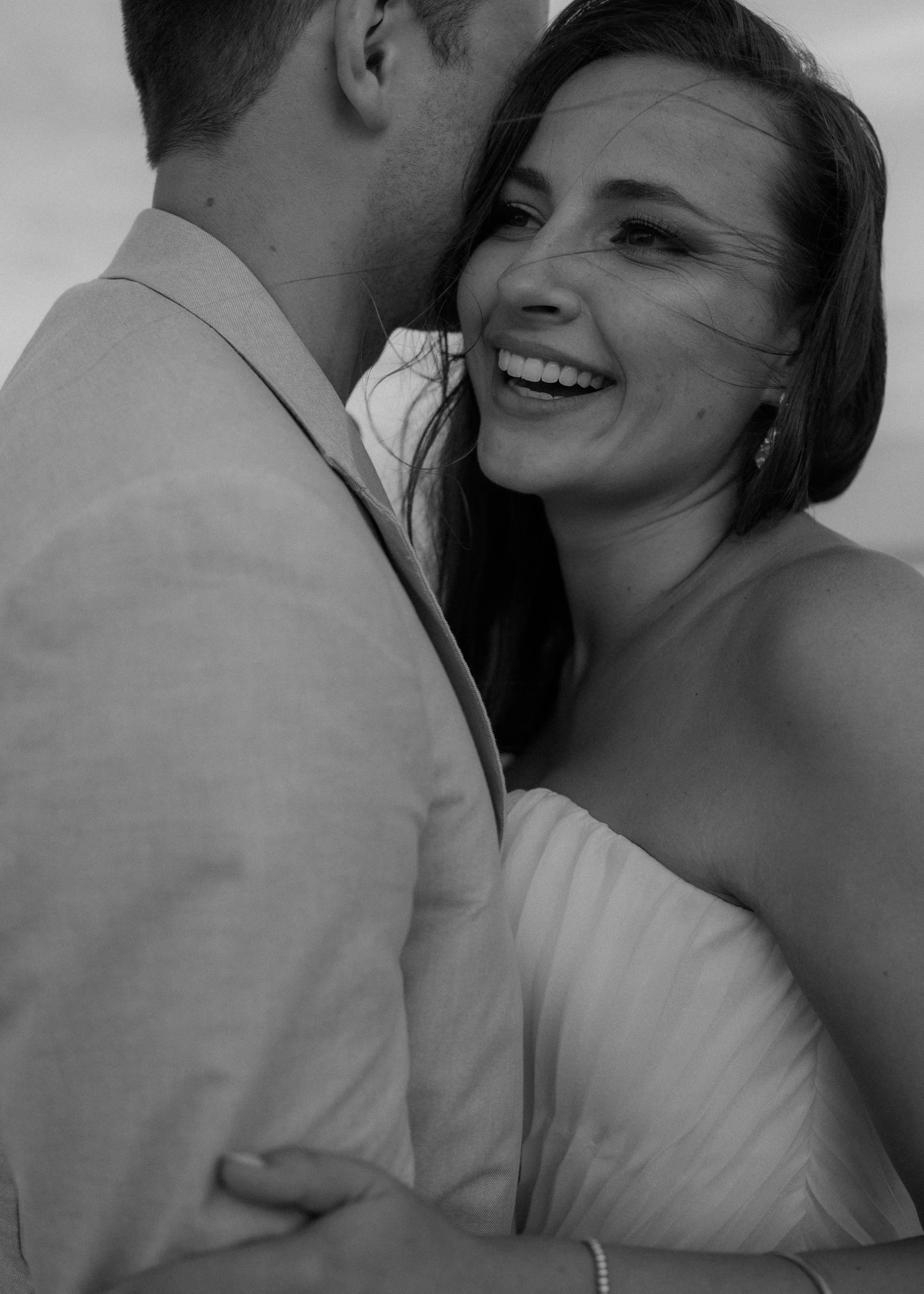 A black and white close-up photo of a couple embracing and smiling, showing joy and affection.