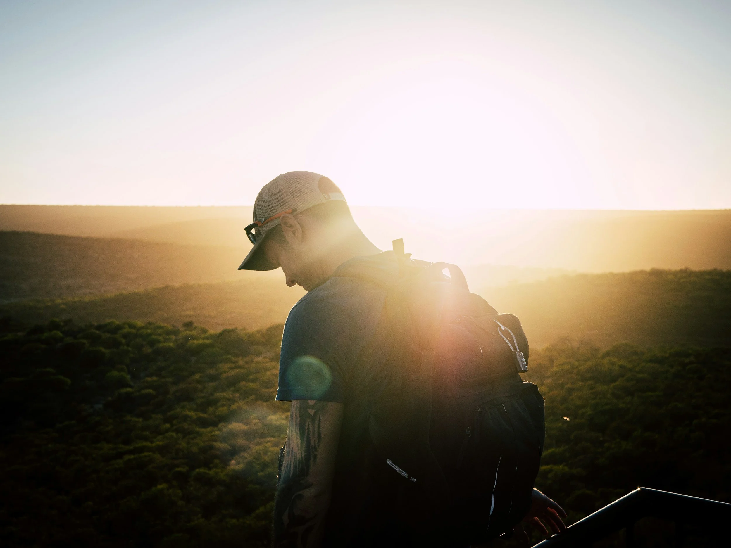 Man sitting on truck bed at sunrise.