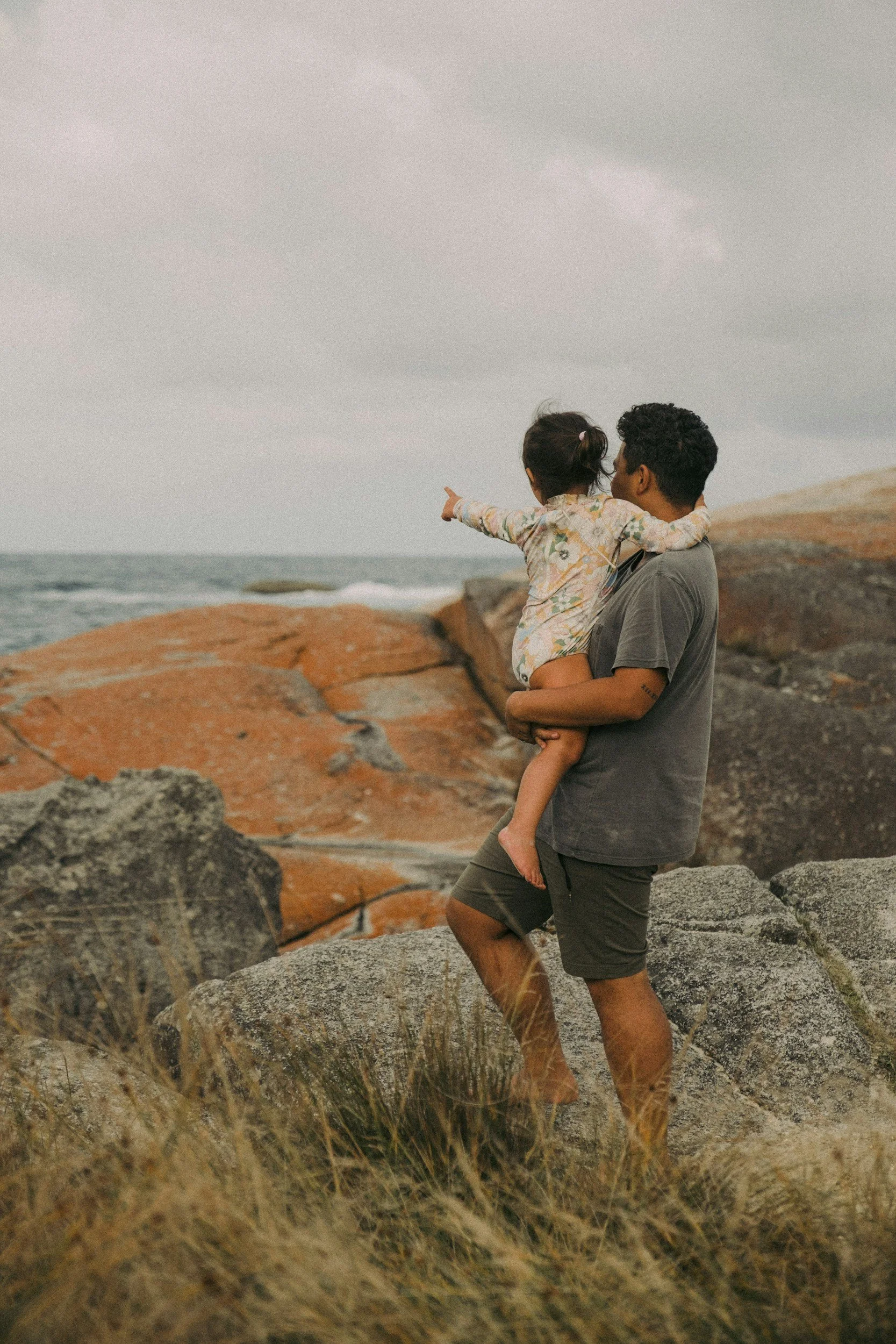 Father holding daughter looking over the ocean.