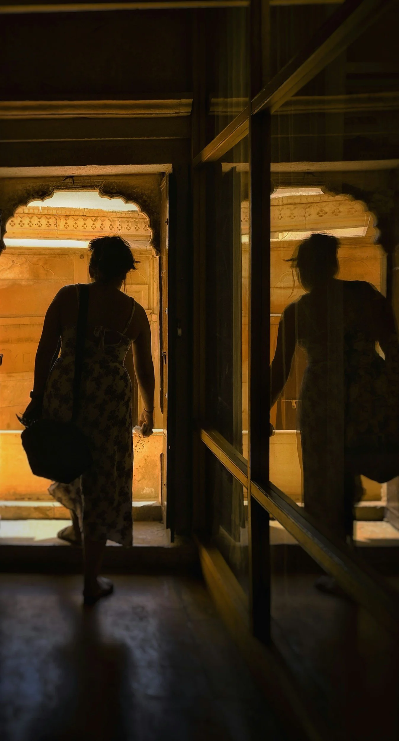 Woman stepping through a doorway with reflection of self in mirror. 