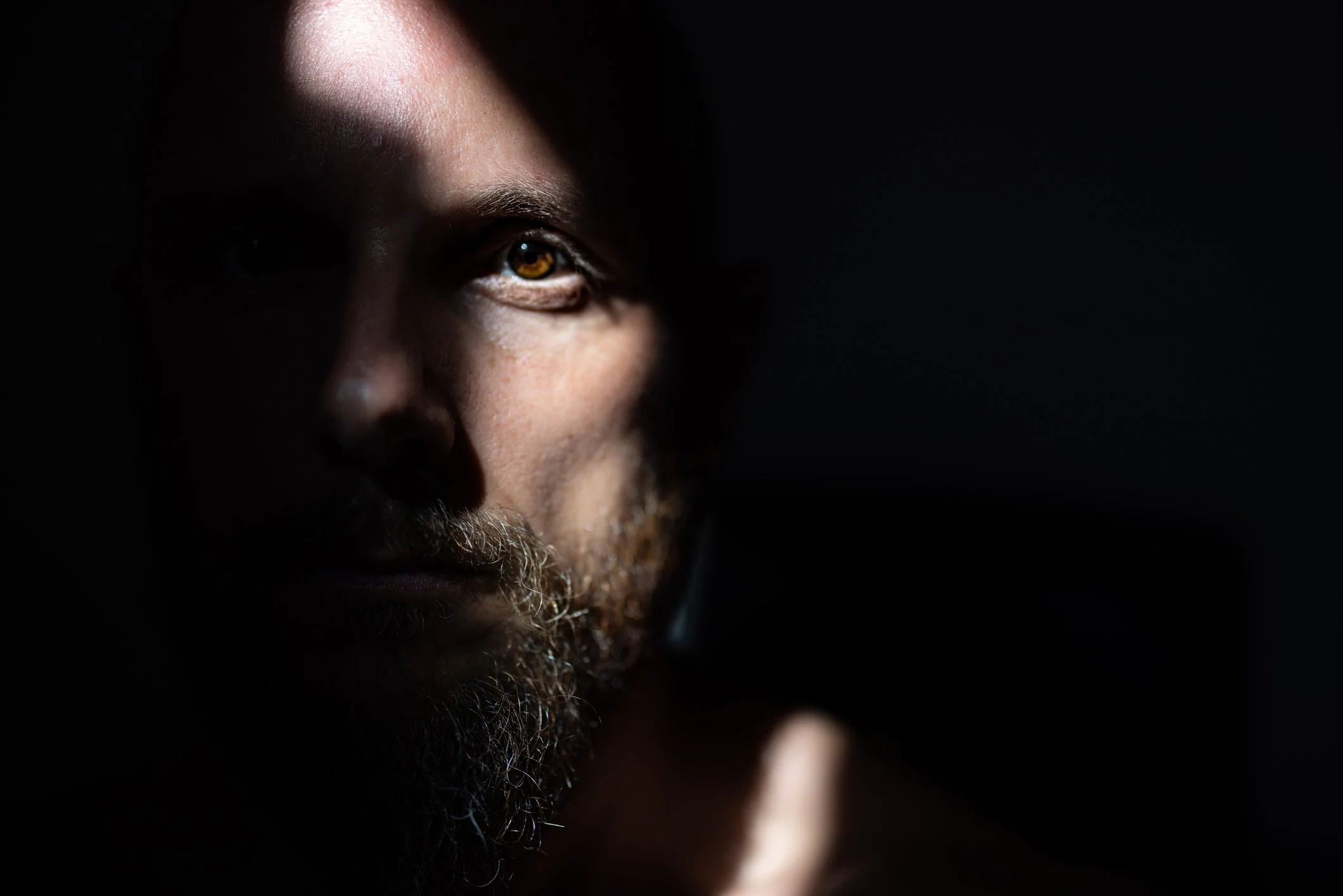 Man in darkness with light cast across his face. 