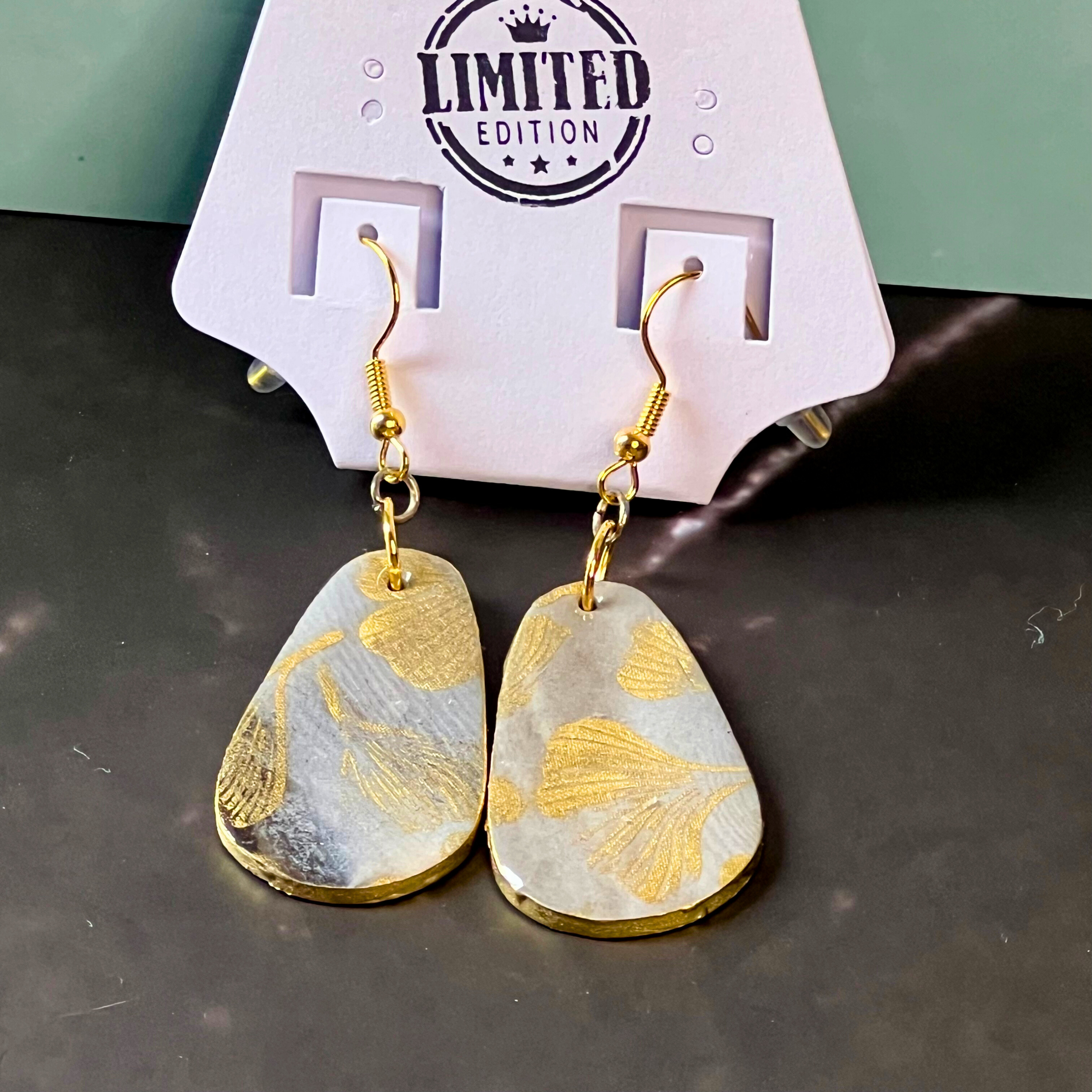 Sophisticated and modern, these earrings combine a black and silver marbled base with a delicate gold ginkgo leaf design. The classic teardrop shape, gold edging, and gold French hooks make them an elegant choice for evening wear or a chic day look w