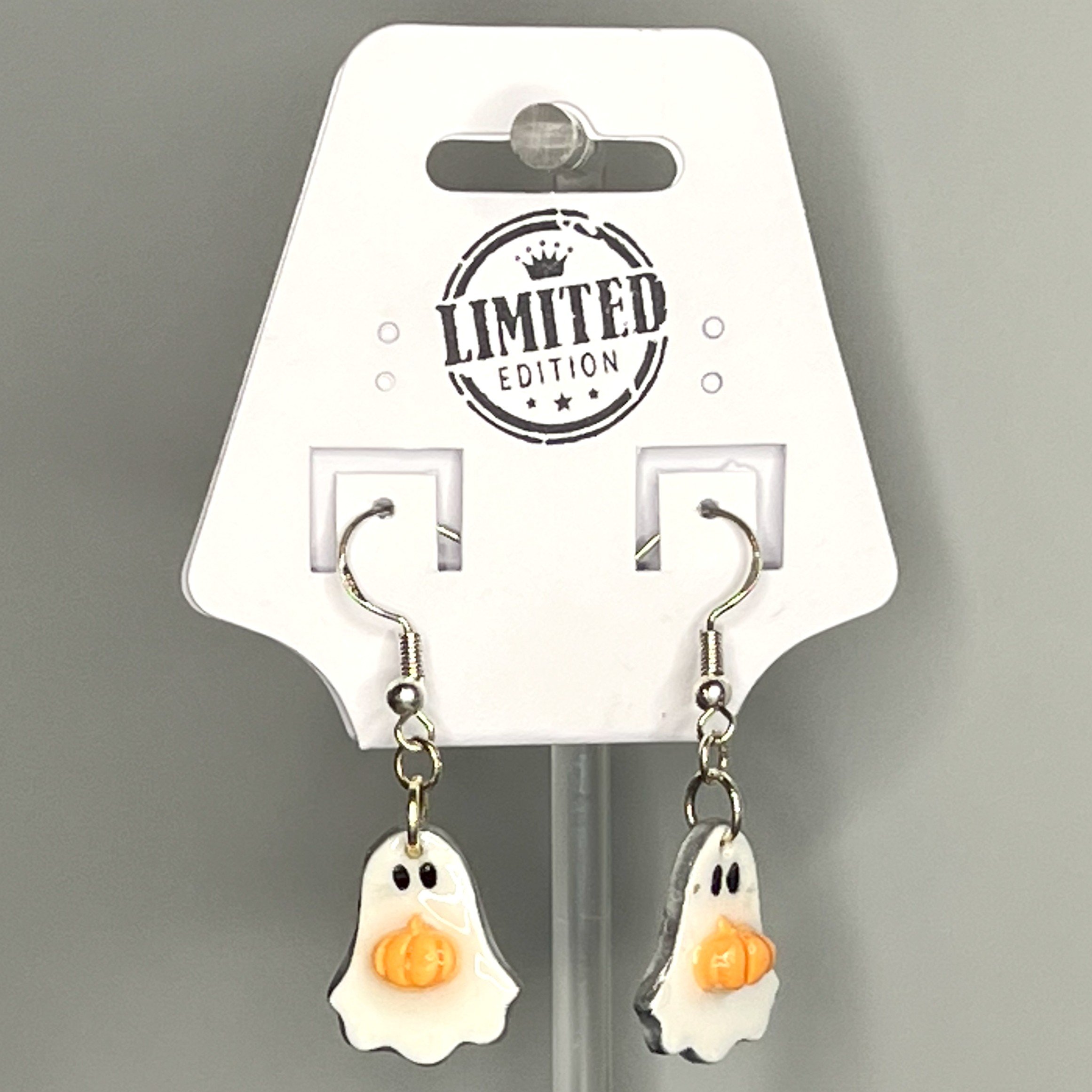 Cute white ghost earrings paired with bright orange pumpkins, displayed on a product card over a black and white marble surface